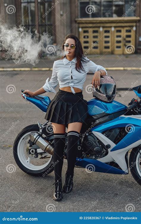 Glamour Woman Biker Smoking Cigarette Leaning Bike Outside Stock Image