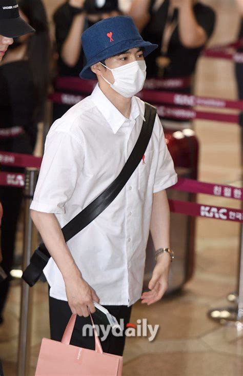 A Man Wearing A Face Mask And Carrying A Pink Bag While Standing In An