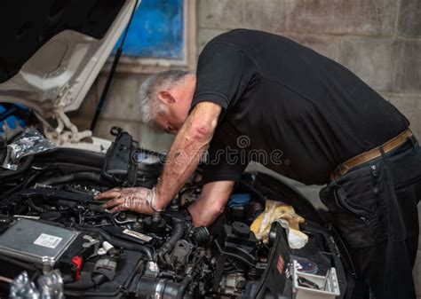 Senior Mechanic Working On Engine Bay Repairing A Oil Leak In Home