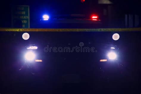 Police Car Seen In Silhouette Against Search Lights And Roof Light Bar