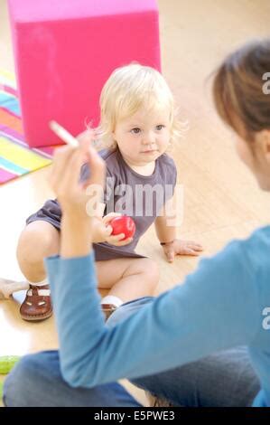 Woman smoking a cigarette near a 4 month old baby Stock Photo - Alamy