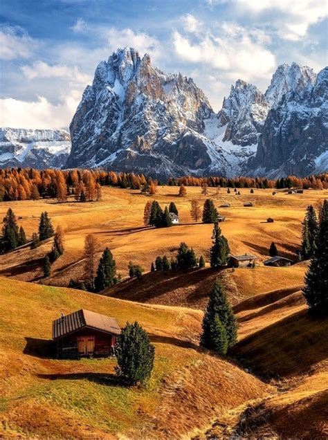 The Mountains Are Covered In Snow And Brown Grass With A Small Cabin