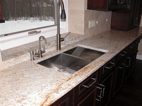 A Beautiful Kitchen With Colonial Cream Granite Countertops And Dark Stained Wood Cabinets Cream