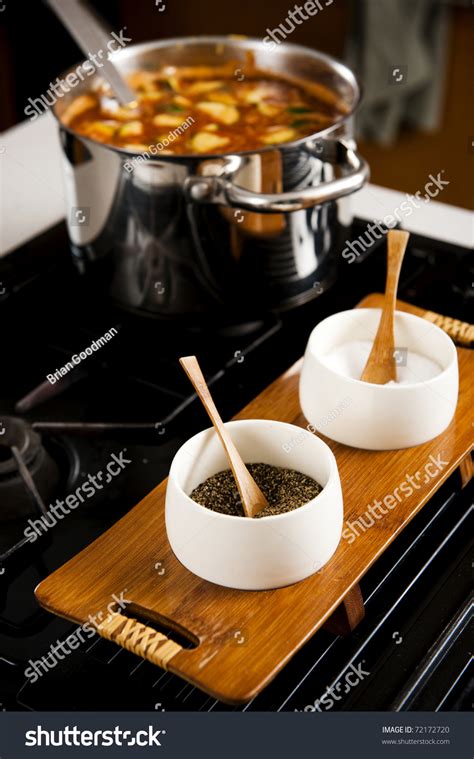 Pot Of Soup On Stove Top With Salt And Pepper In Foreground Stock Photo