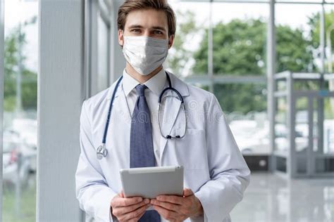 Male Medical Doctor Portrait In Hospital With Face Masks Looking At