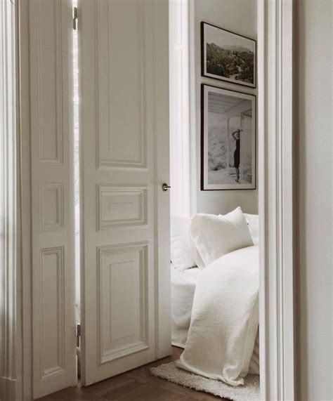 An Open Door Leading To A Bedroom With White Bedding And Pillows On The