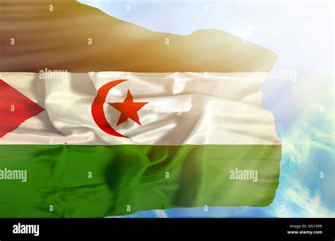 Western Sahara Waving Flag Against Blue Sky With Sunrays Stock Photo