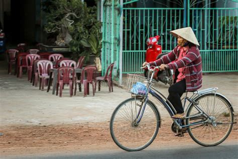 Local Vietnamese In A National Hat Rides A Bicycle On The Road