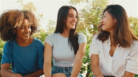 Mujeres jóvenes multiétnicas felices hablando mientras están sentadas