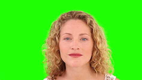 Curly Blond Haired Woman Putting On Make Up Against A Green Screen