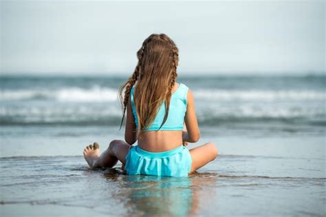 Niña sentado en playa vista trasera Foto Gratis