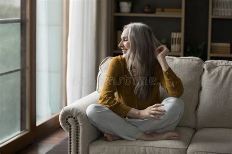 Happy Pretty Mature Grey Haired Woman Resting On Cozy Sofa Stock Image