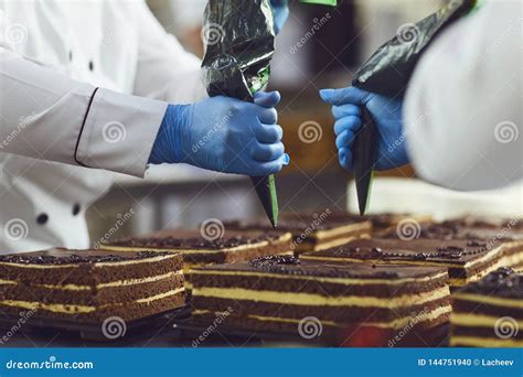 Os Pasteleiros Decoram O Creme De Um Saco Em Um Bolo De Chocolate Em