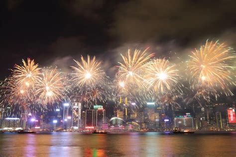 Fireworks Are Lit Up In The Night Sky Over Water And Cityscape With