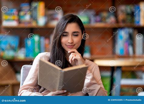 Carefree Arab Woman Reading Favorite Book While Sitting Alone In Cafe