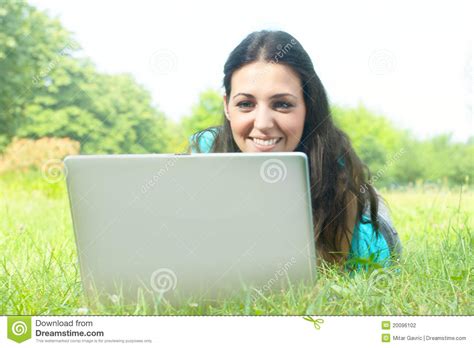 Menina Bonito Que Encontra Se Na Grama No Parque Usando A Foto De Stock