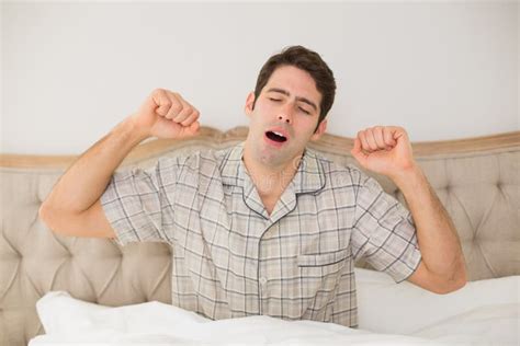 Hombre Joven Que Estira Sus Brazos En Cama Foto De Archivo Imagen De