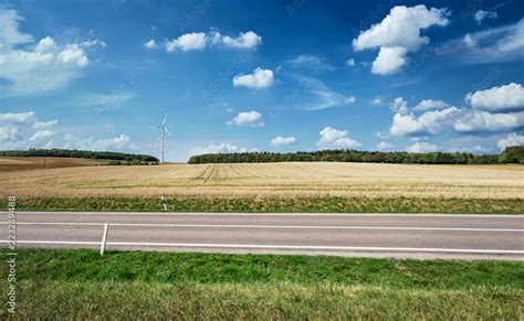 Landstraße seitlich vor Landschaft mit Windkraft im Sommer Saarland bei