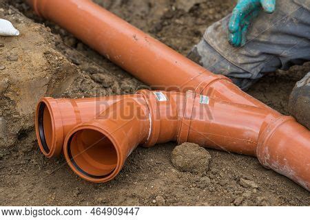 Construction Worker Puts Pvc Sewer Pipes On Site Branches In The