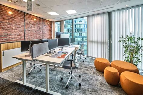 An Office With Two Desks And Three Chairs In Front Of A Brick Wall That