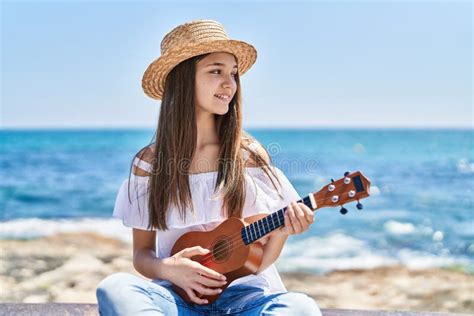 Adorable Girl Tourist Smiling Confident Playing Ukulele At Seaside