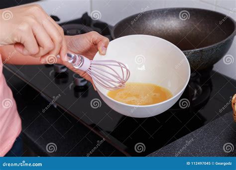 Close Up Of Hand Cooking And Whisking Eggs In A Bowl In Kitchen Stock