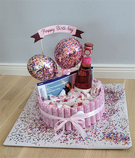 A Pink Birthday Cake With Confetti Balloons And Wine Bottle On The Table