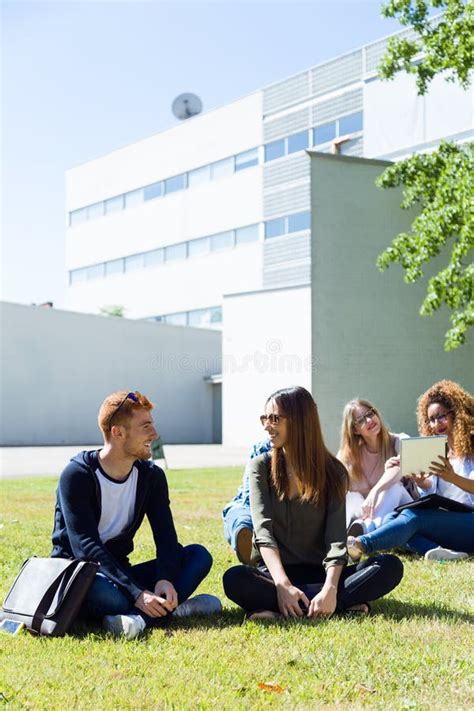 Happy Students Sitting Outside On Campus At The University Stock Photo