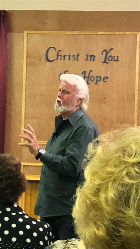 a man standing in front of a group of people with his hands out to the side