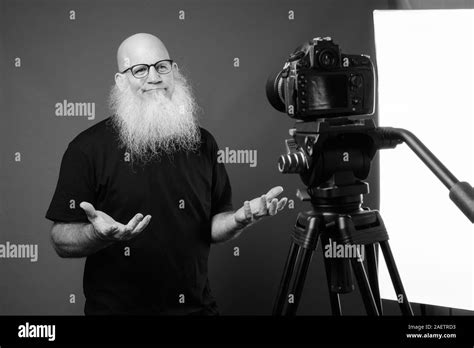 Mature Bald Man With Long Beard Vlogging In Black And White Stock Photo