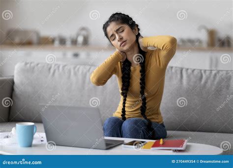 Tired Indian Woman Suffering Neck Pain While Working With Laptop At