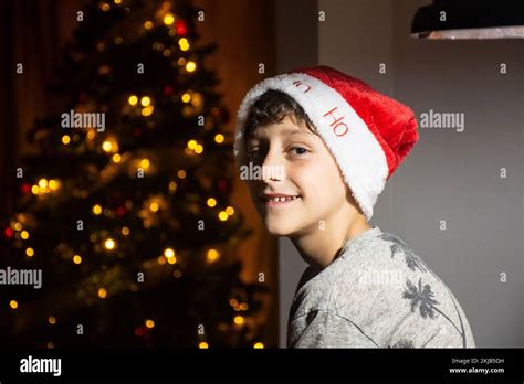 Boy Smiling Next To The Christmas Tree With A Christmas Hat Green Eyes