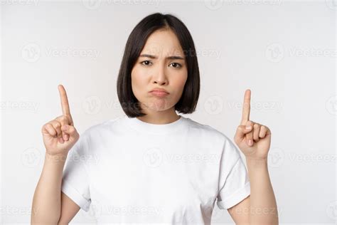 Sad And Disappointed Young Asian Woman Pointing Fingers Up Showing