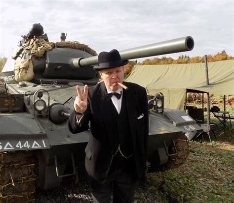 A Man In A Suit And Top Hat Standing Next To A Tank