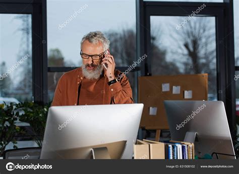 Mature Businessman Talking Smartphone Looking Computer Monitor While Working Office Stock