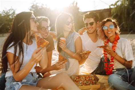 Grupo De Jóvenes Amigos Haciendo Un Picnic Comiendo Pizza Brindando Con