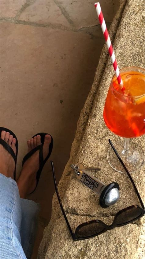 A Person S Feet With Sandals And A Drink On The Ground Next To Them