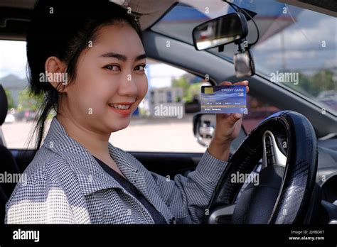 Happy Beautiful Asian Woman Sitting Inside Her Car Showing Credit Card Payment At A Gas Station