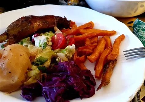 A White Plate Topped With Meat And Veggies Next To A Fork On A Table