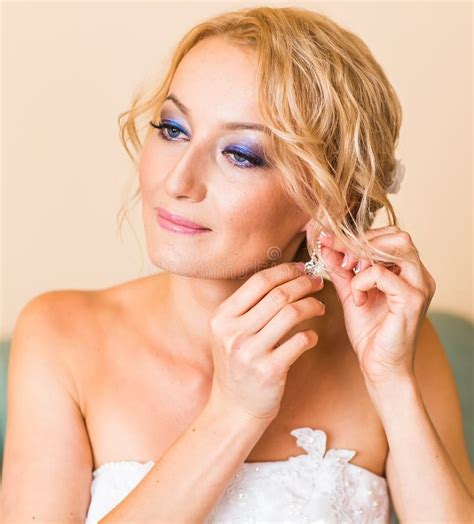 Beautiful Elegant Bride Putting On Earrings Closeup Wedding