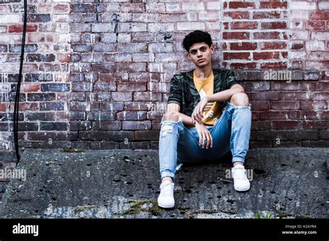 Male Sitting Against Brick Wall Stock Photo Alamy