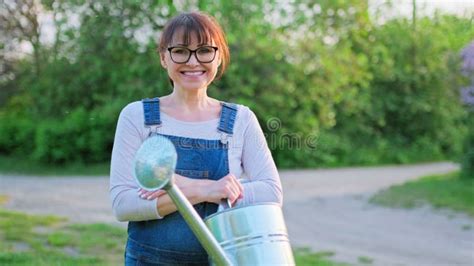 Outdoor Portrait Of Mature Smiling Woman With Watering Can Stock Video