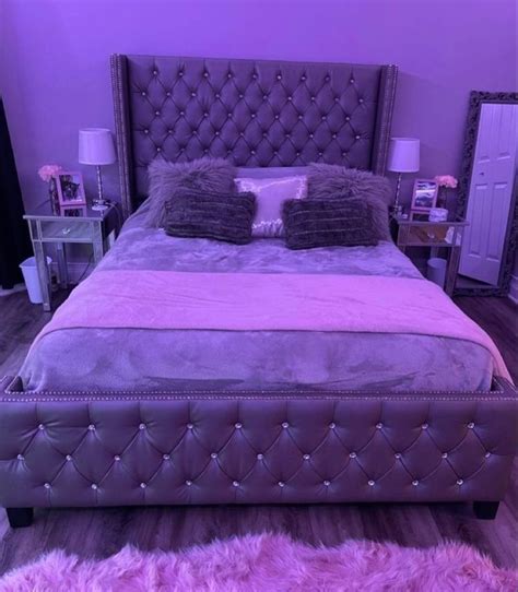 A Large Bed With Two Pillows On Top Of It And Purple Walls In The