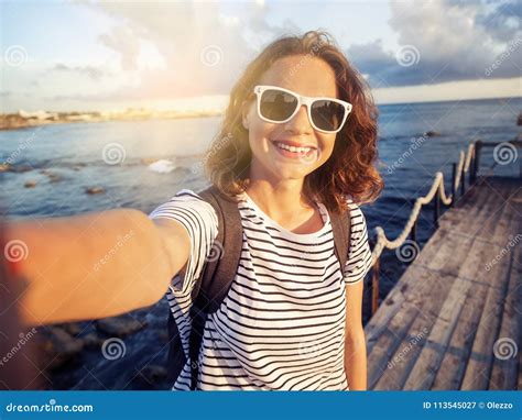 Beautiful Young Woman Doing Selfie On The Sea And City Background Stock