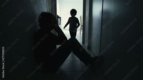 Depressed Father Being Consoled By Son Sitting In Corridor In