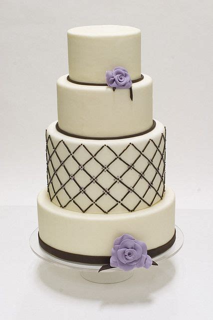 A Three Tiered Cake With Purple Flowers On Top