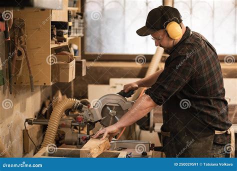 Carpenter Worker In Protective Apron And Headphones Use Modern Grinder