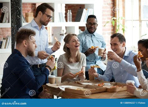 Happy Diverse Team People Talking Laughing Eating Pizza In Office Stock