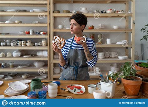 Hungry Female Pottery Artist In Apron Having Breakfast While Standing