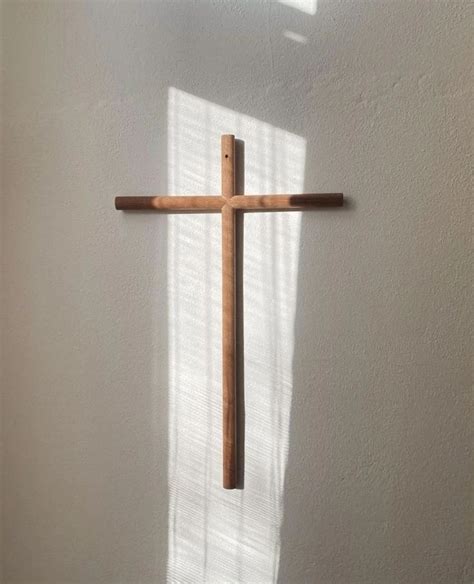 A Wooden Cross Hanging From The Side Of A Wall In Front Of A White Wall